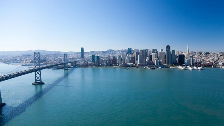 Foto der Stadt San Francisco. Links im Bild die Bay Bridge und dahinterliegend die Skyline der Stadt.