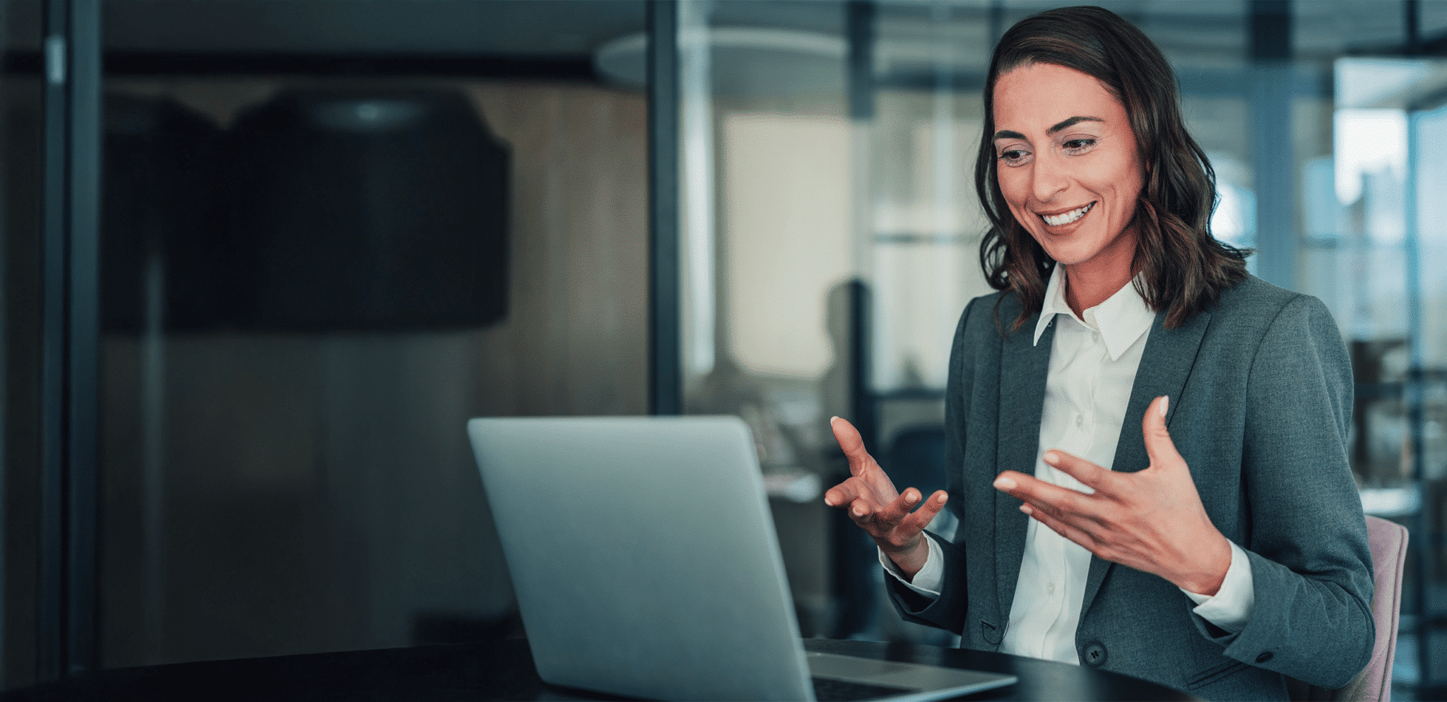 Woman sitting in front of a laptop in business attire having a conversation via a video call
