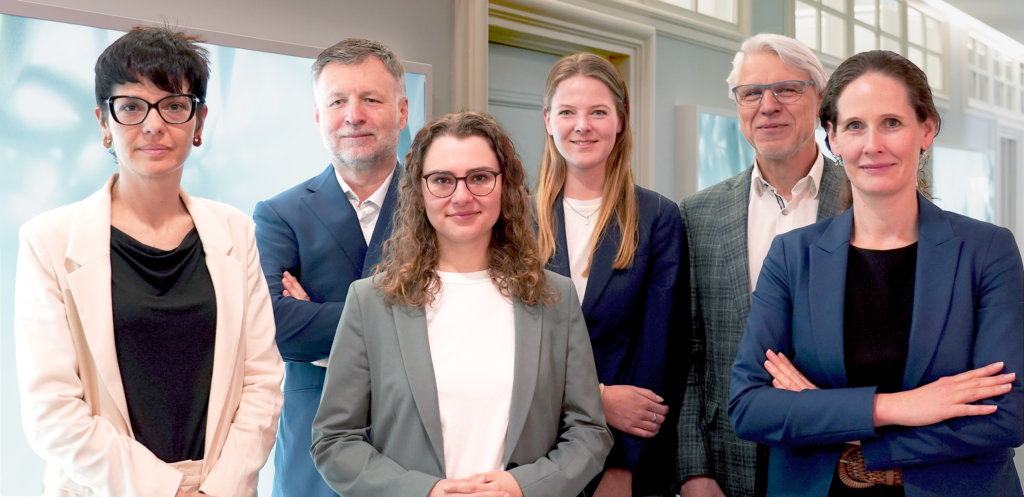 Six people - four women and two men - in business attire standing towards the camera