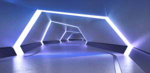 A futuristic, empty tunnel with angular white LED light frames lining the walls and ceiling, creating a glowing geometric pathway with cool blue lighting and a smooth reflective floor.