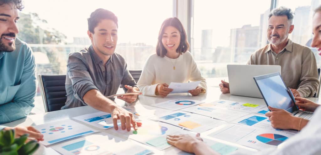 Business team analyzing charts and data reports together in a bright office.