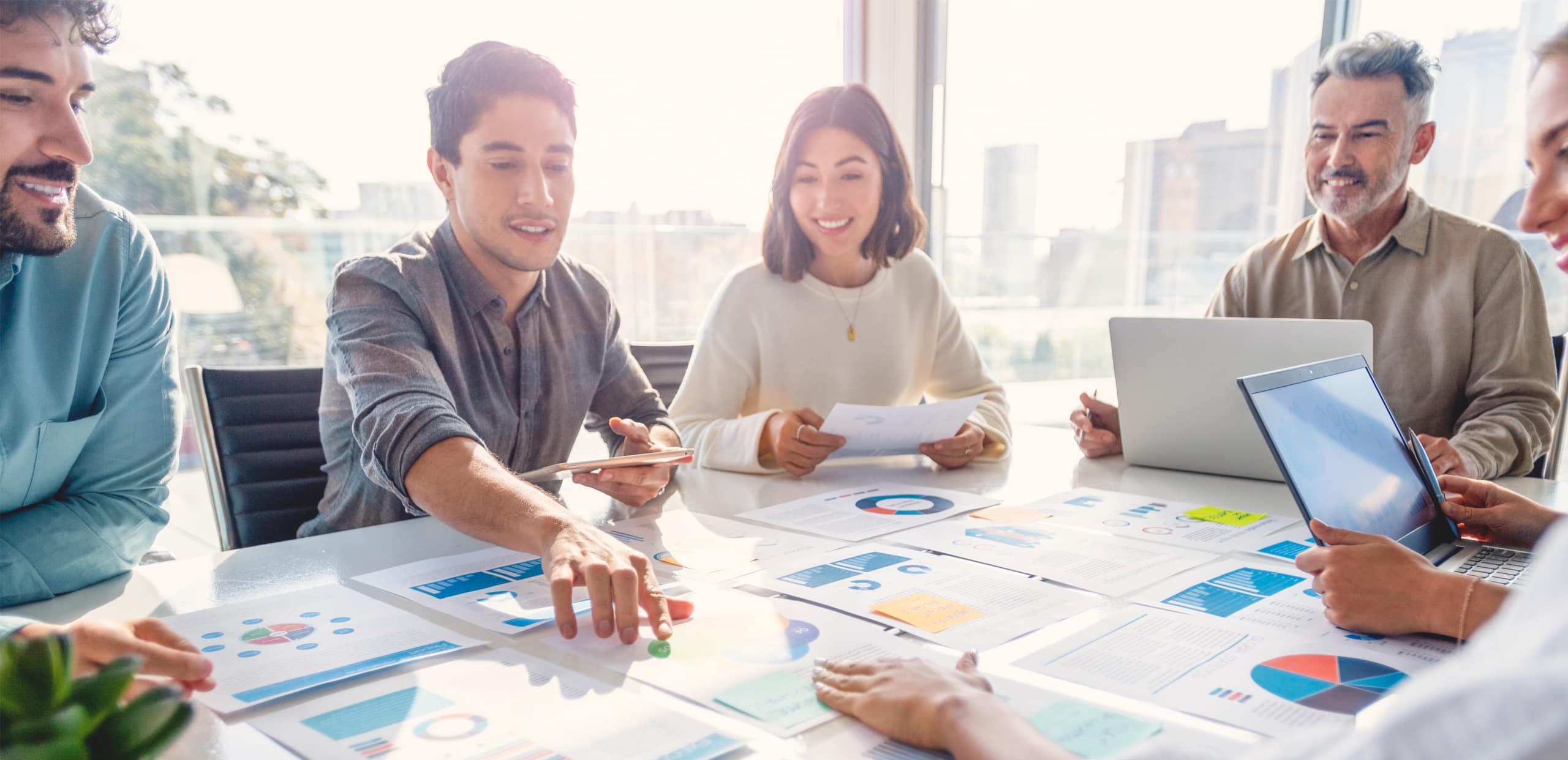 Business team analyzing charts and data reports together in a bright office.